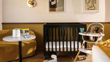 Una habitación moderna para bebés con una cuna, una trona y un asiento para bebé.