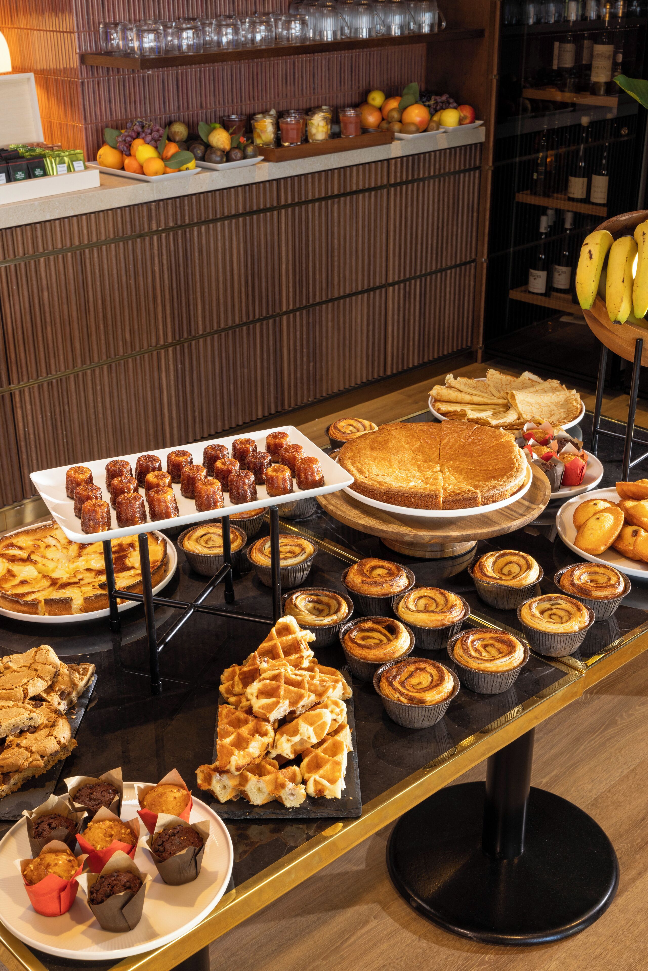 Une table de buffet proposant diverses pâtisseries, notamment des tartes, des muffins et des gaufres.