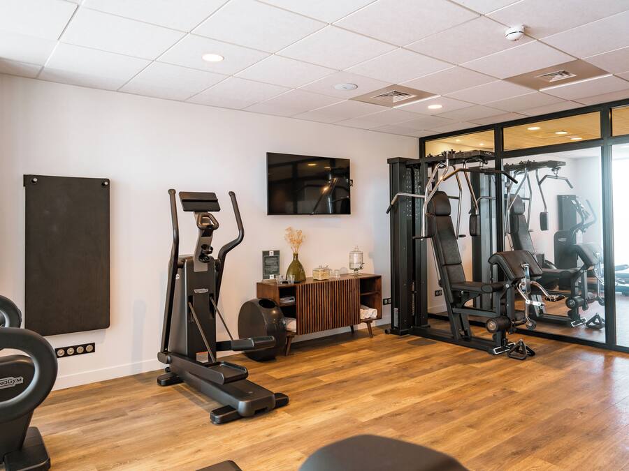 Un gimnasio con equipo de ejercicio, un espejo y piso de madera.