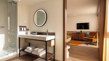 Un baño moderno con cabina de ducha de vidrio, tocador con espejo y suelo de madera.