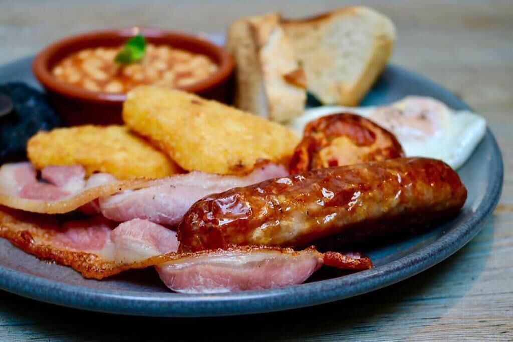 A plate of breakfast food including sausages, bacon, eggs, and toast.