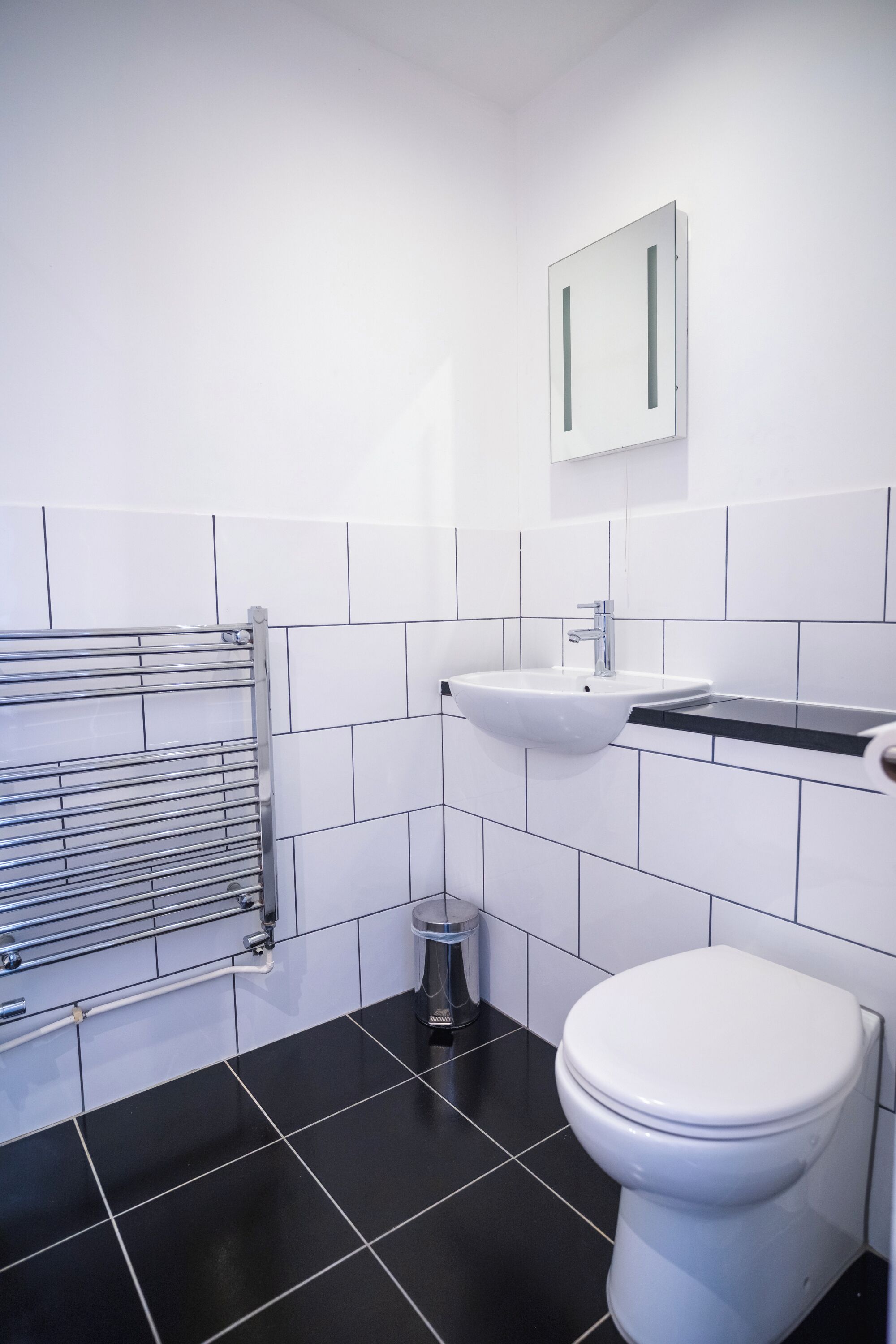 A modern bathroom with a white sink, a toilet, and a towel rack.