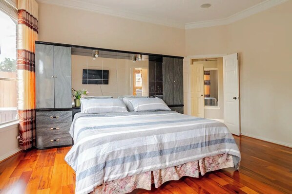Une chambre à coucher avec un grand lit, une armoire, un miroir et une porte donnant sur une autre pièce.