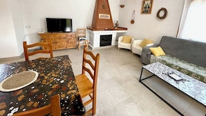 A living room with a fireplace, a sofa, a dining table with chairs, and a television. - SAONA VILLAS (VN VERDA): villa for 6 people, private pool, wifi, air co (Les Tres Cales)