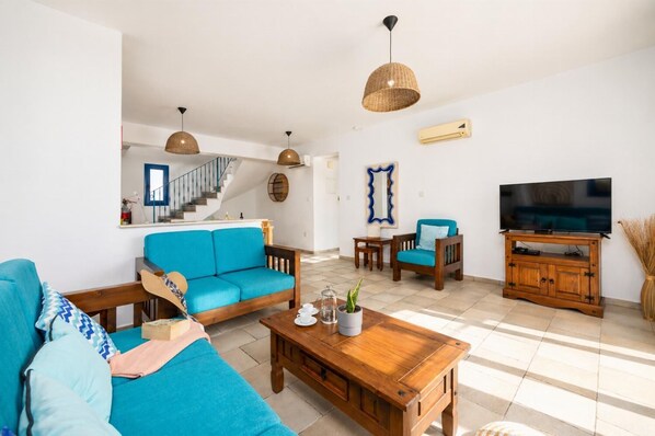 A living room with a sofa, coffee table, TV stand, and hanging lights.