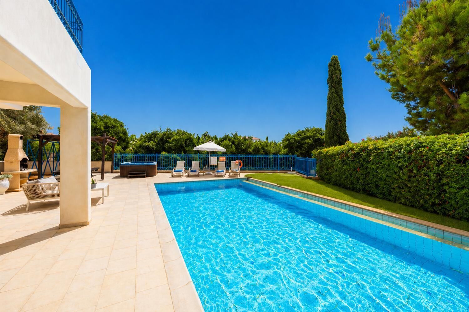 A swimming pool with lounge chairs, a hot tub, and a pergola.