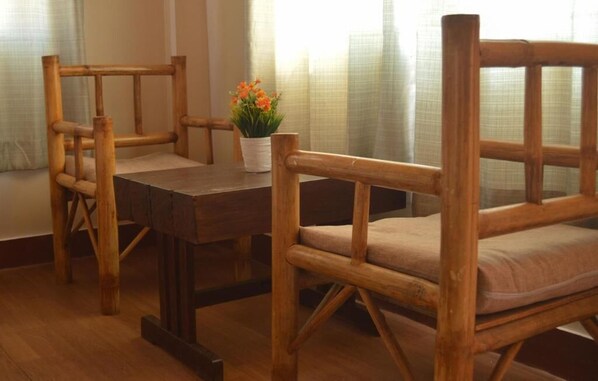 A wooden dining table with chairs, a potted plant, and a window with curtains. - Doors Hotel (Kathmandu)