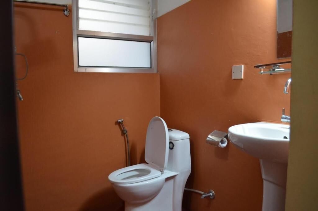A small bathroom with a white toilet, a sink, and a window above the toilet.