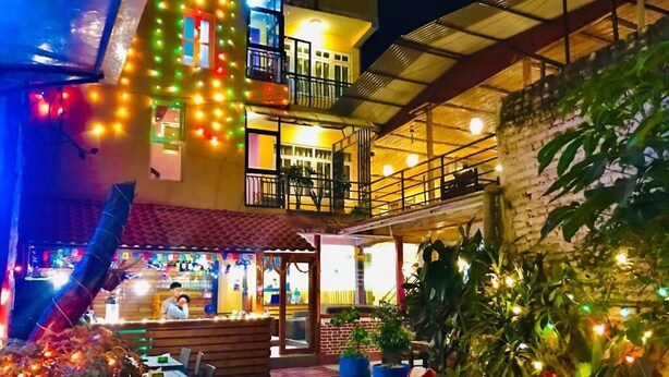An outdoor dining area with tables and chairs, surrounded by potted plants and illuminated by string lights. - Doors Hotel (Kathmandu)