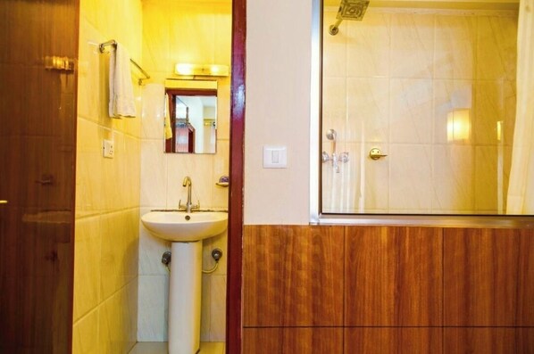 A bathroom with a sink, mirror, and shower. - Doors Hotel (Kathmandu)