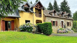 Un edificio de dos pisos con fachada de piedra, un balcón y un césped bien cuidado.