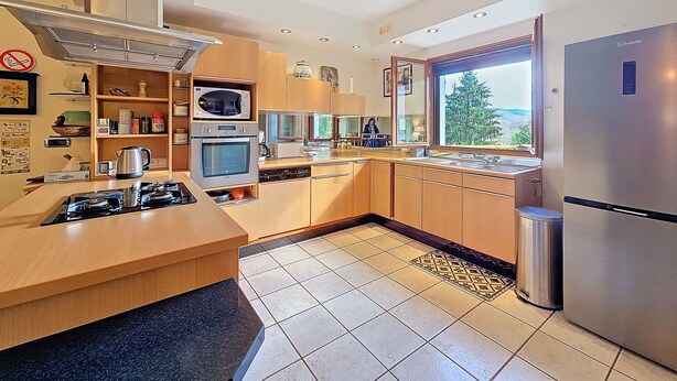Una cocina moderna con una isla central, horno empotrado, microondas y refrigerador de acero inoxidable.
