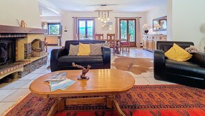 Una sala de estar con chimenea, un sofá, una mesa de centro y un comedor con sillas y una mesa.