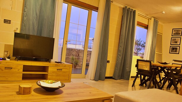 Un salon avec un meuble TV en bois, une table à manger et un canapé.