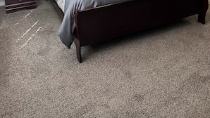 A bedroom with a large bed, two bedside tables, a nightstand, and a decorative wall piece.