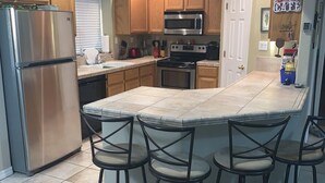 A modern kitchen with a central island, stainless steel appliances, and wooden cabinets.