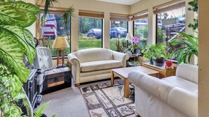 A cozy living room with a beige sofa, a coffee table, and various potted plants.