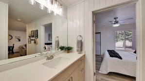 A modern bathroom with a large mirror, a sink, and a ceiling fan.