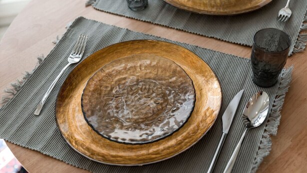 Una mesa de madera con un plato, cubiertos y un vaso.