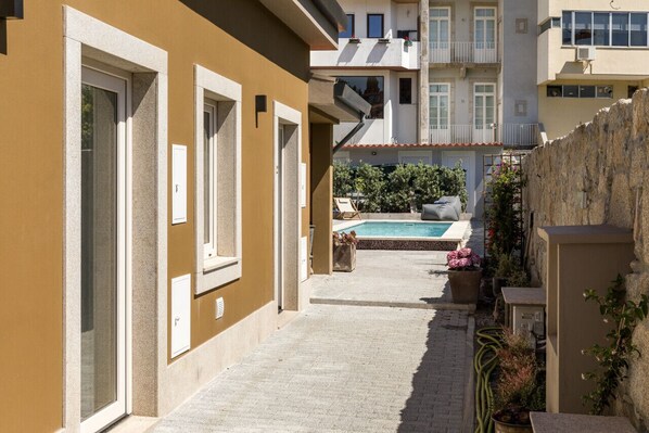 Stroll through a quiet alleyway to a serene pool area surrounded by residential buildings with balconies.