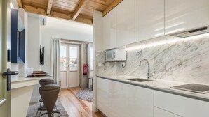 A modern kitchen with marble countertops, a built-in microwave, and a stainless steel sink.