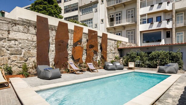 A swimming pool with lounge chairs and a stone wall.