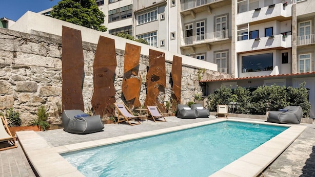 A swimming pool with lounge chairs and a stone wall. - Spacious Bright Studio by PortoDreamStays (Porto)