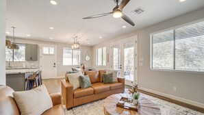 A spacious living room with a brown leather sofa, a wooden coffee table, and a ceiling fan. - Games & Outdoor Seating: Cabin in Scenic Payson! (Payson)
