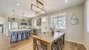 A modern kitchen with a central island, bar stools, and pendant lighting. - Games & Outdoor Seating: Cabin in Scenic Payson! (Payson)