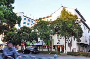 A street view with a traditional building, a modern building, and a tree-lined sidewalk. - Xingle Hotel (Suzhou)