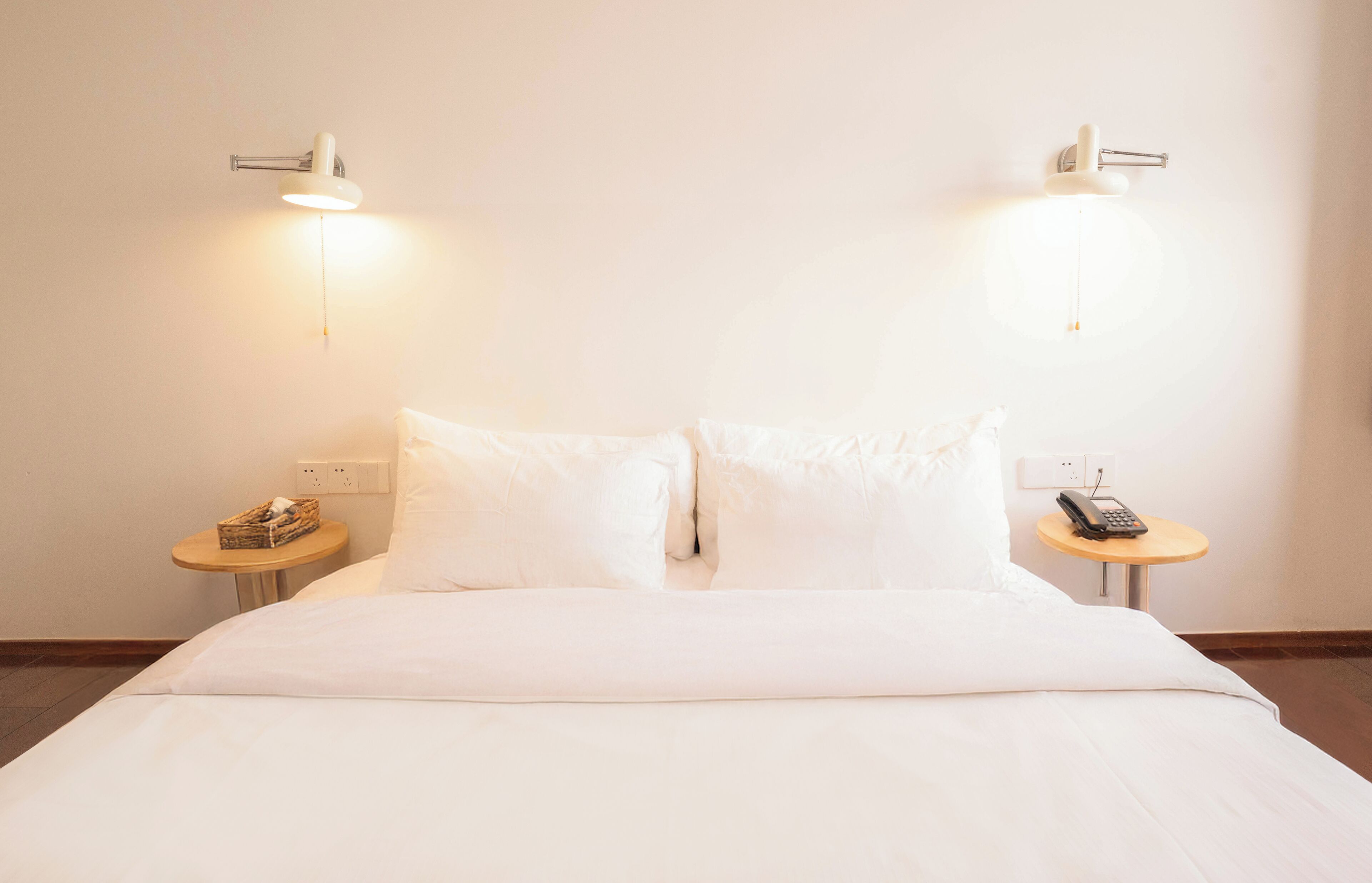 Une chambre d’hôtel avec un lit soigneusement fait, deux tables de chevet avec des lampes et un téléphone sur l’une des tables.
