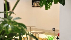 A modern indoor space with a minimalist design, featuring a concrete floor, a few tables, and a bookshelf against the wall. - Xingle Hotel (Suzhou)