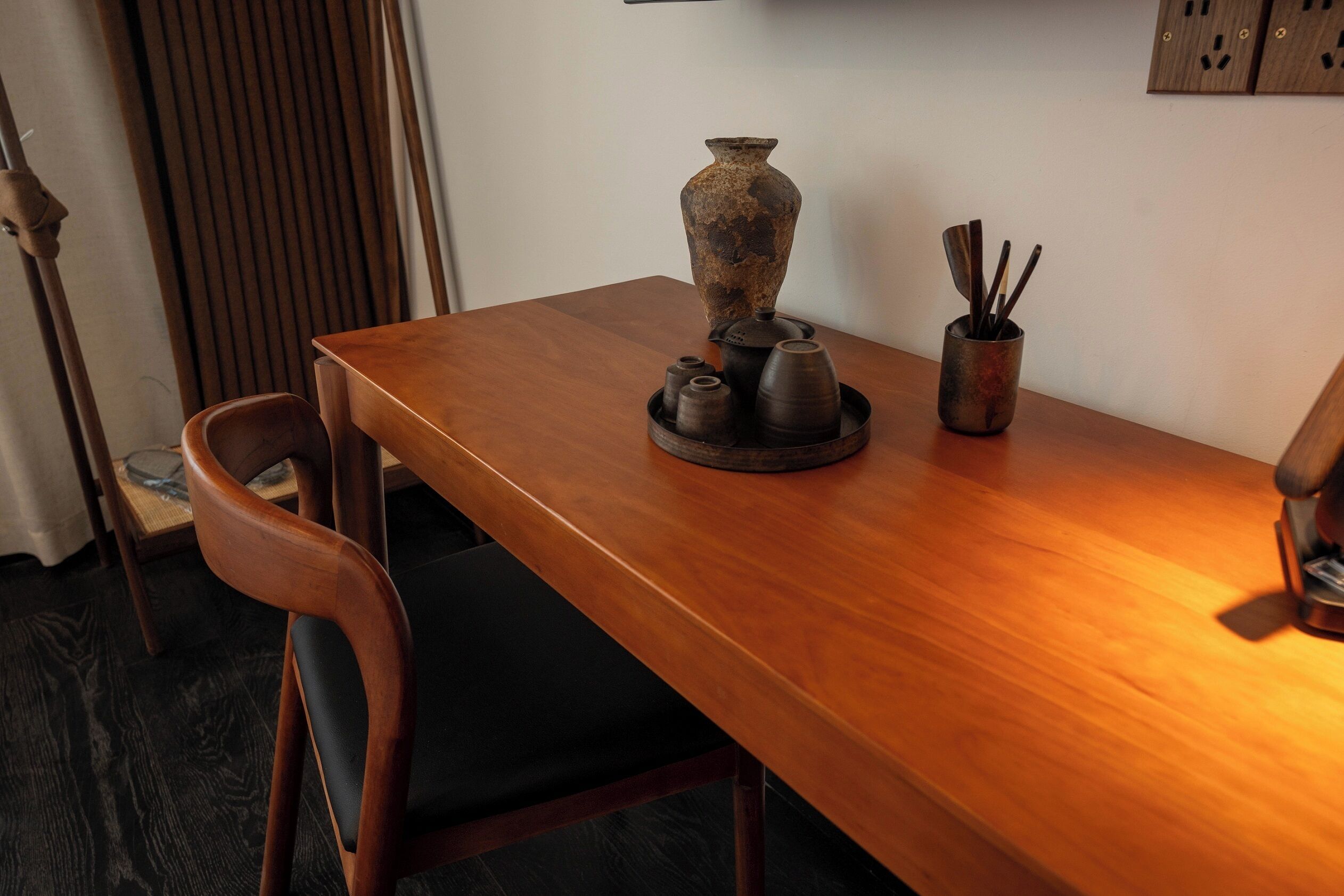 Un tavolo di legno con un vaso, una tazza e posate, e una sedia.