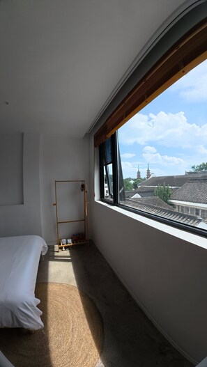 A bedroom with a bed, a wooden shelf, a window with a view of traditional buildings. - Xingle Hotel (Suzhou)