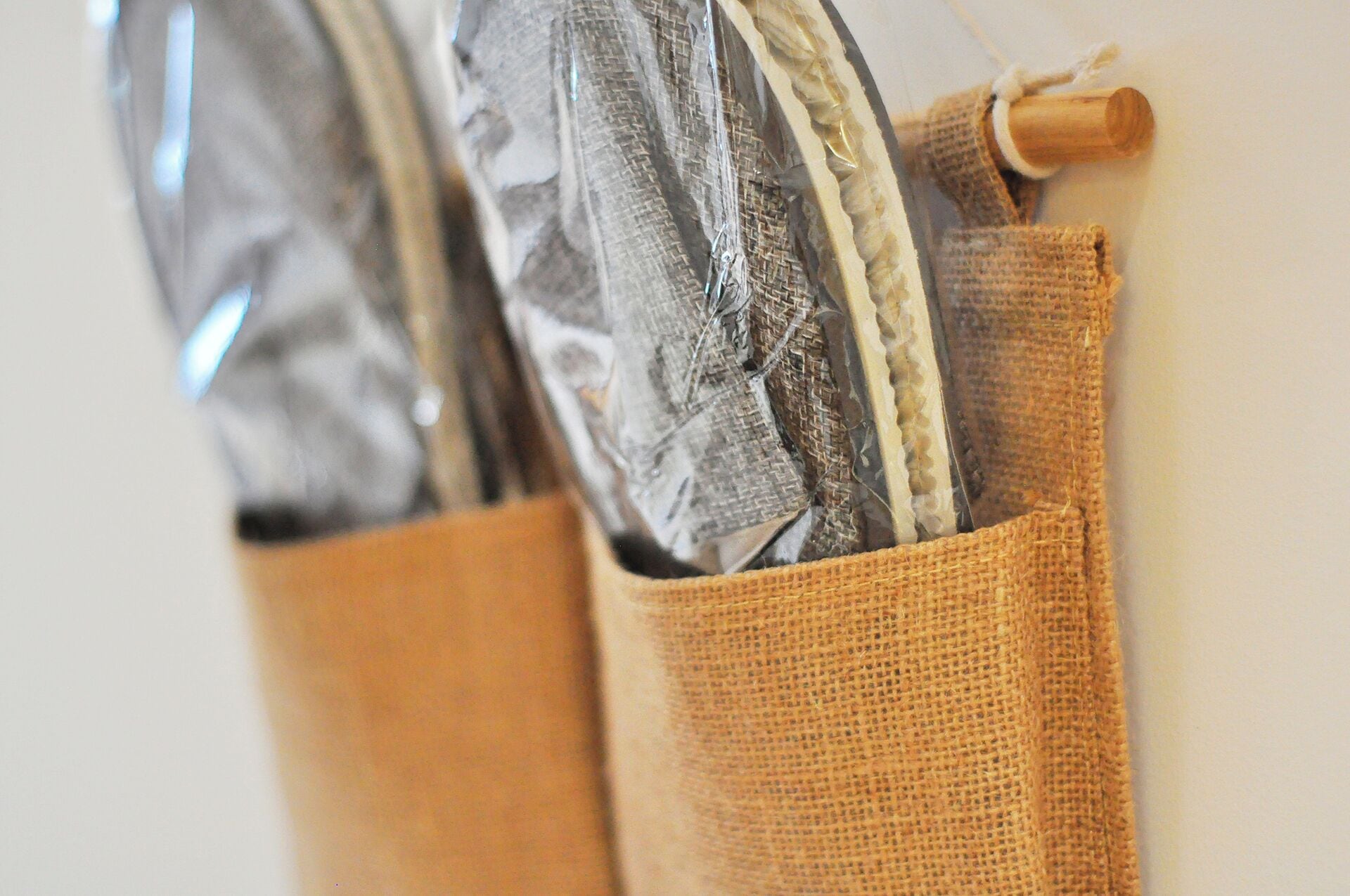 Gros plan sur un sac en toile de jute doté d’une anse en bois, contenant des vêtements pliés.