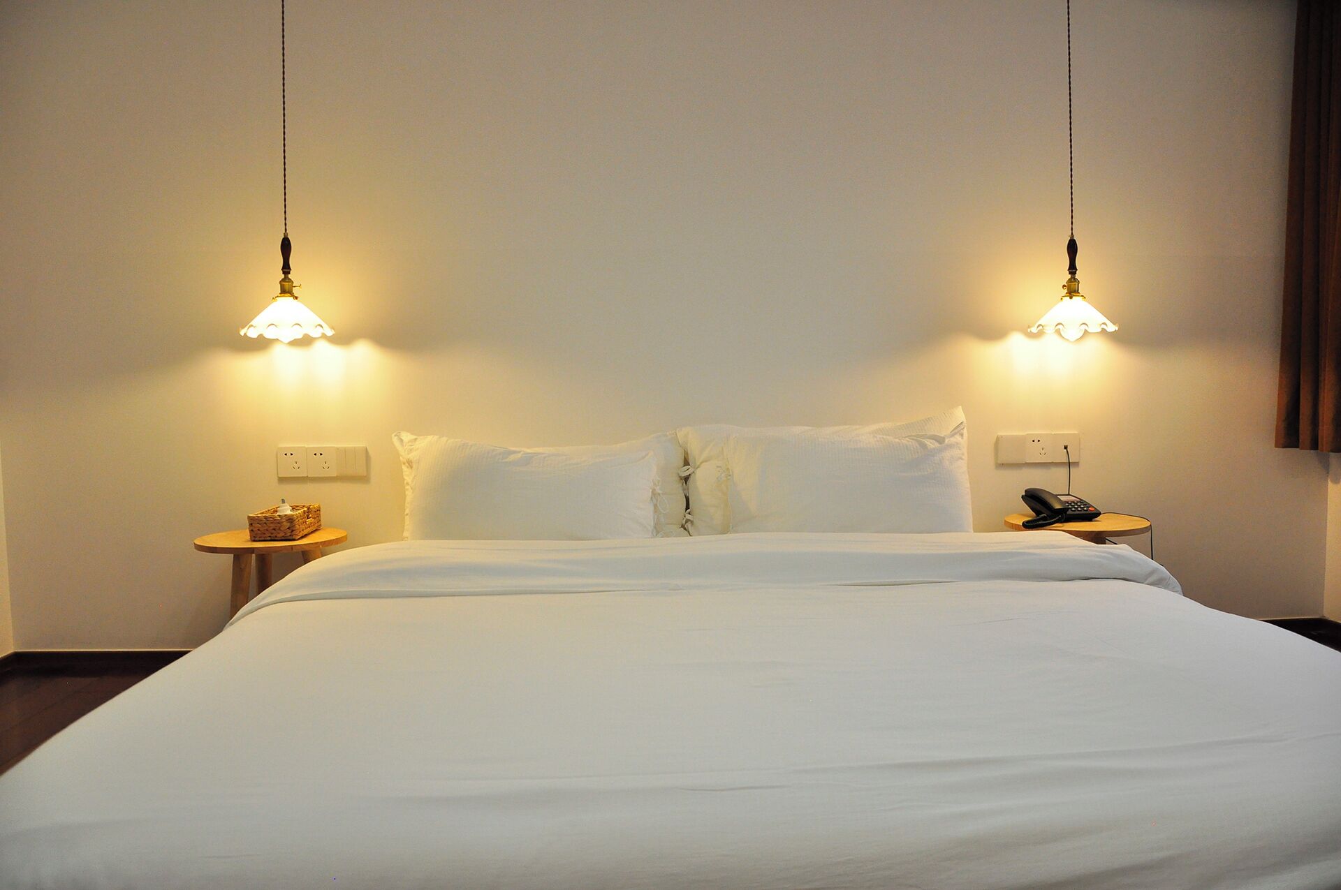 A hotel room with a bed, two bedside tables, a lamp, and a phone on one of the tables.