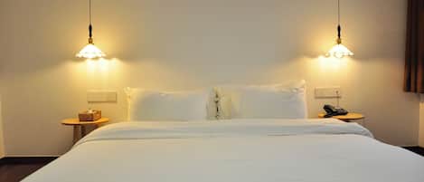 A hotel room with a bed, two bedside tables, a lamp, and a phone on one of the tables.