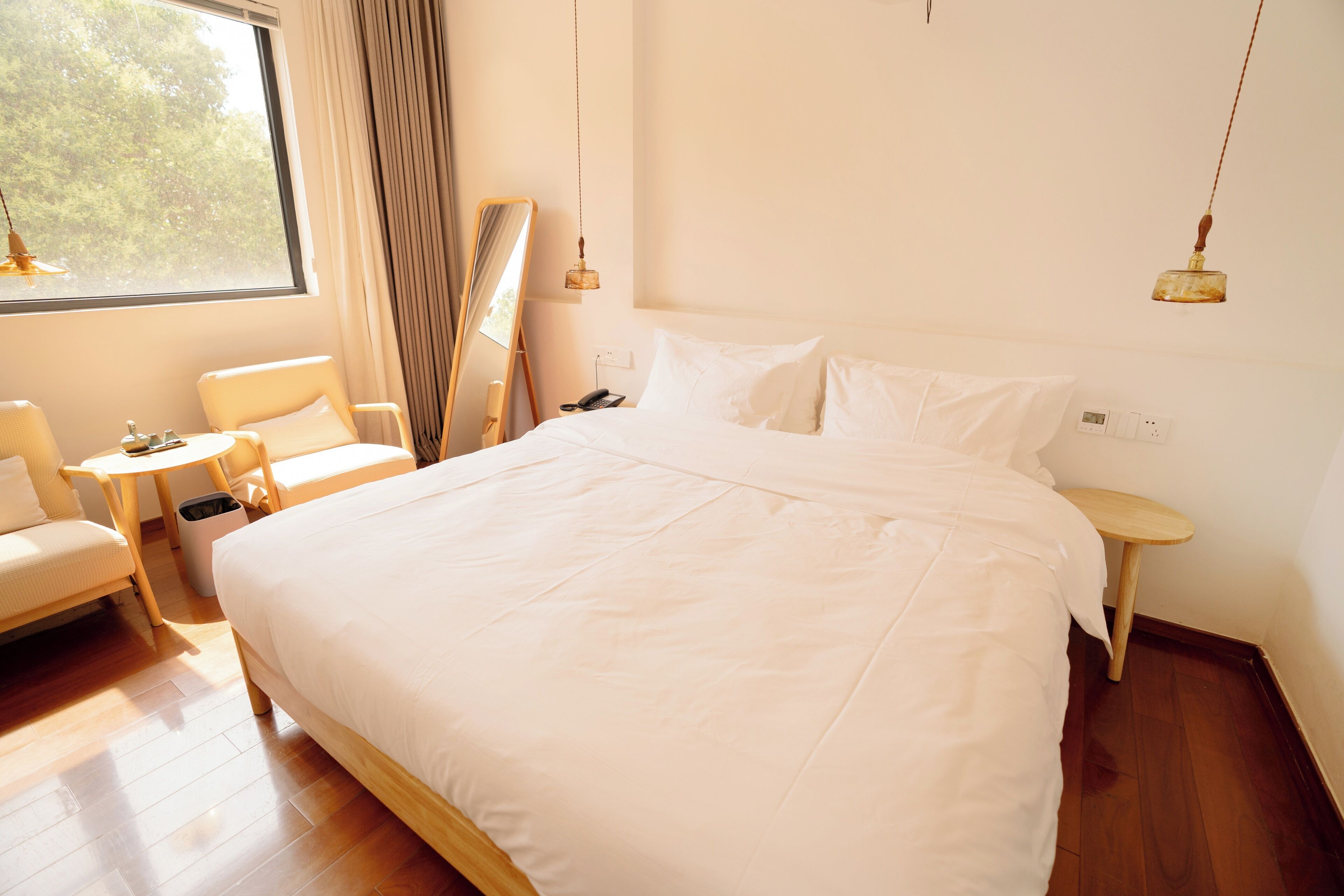 A neatly arranged bedroom with a large bed, bedside tables, a chair, and a window with curtains.