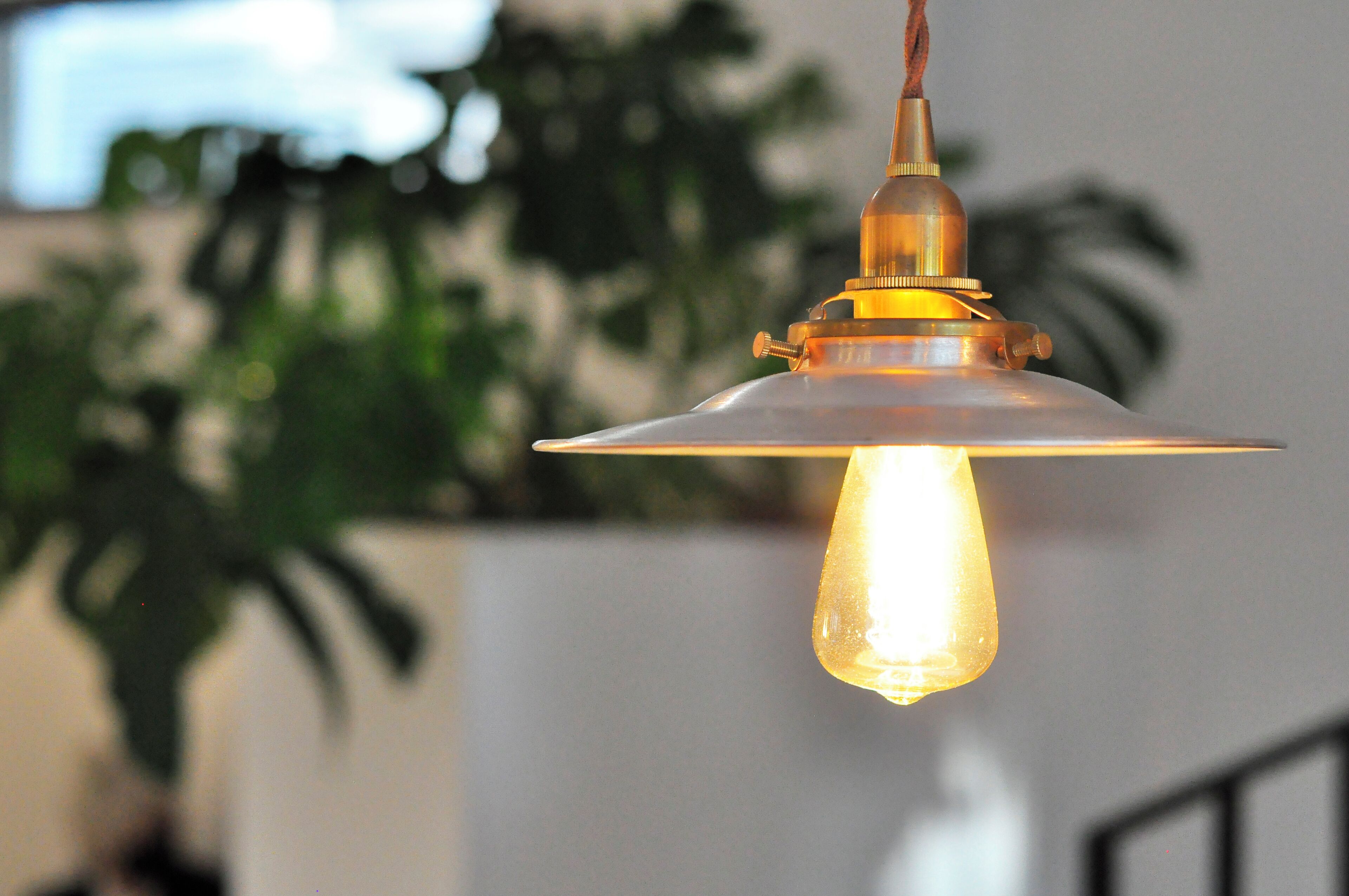 Una lampada a sospensione con paralume in vetro trasparente e lampadina a filamento a vista.