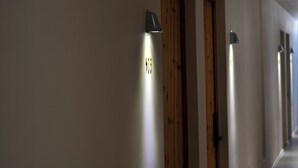 A hallway with doors and wall-mounted light fixtures. - Xingle Hotel (Suzhou)