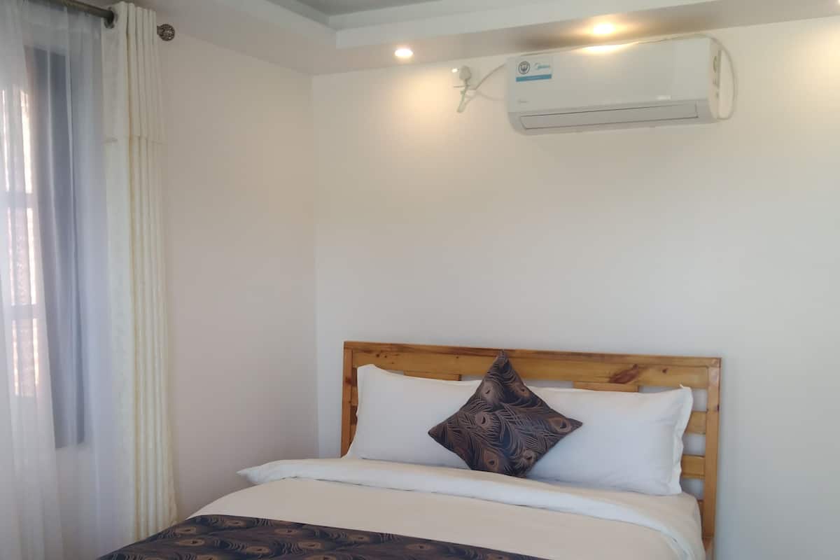 A neatly made bed with a wooden headboard, white bedding, and a patterned throw blanket.