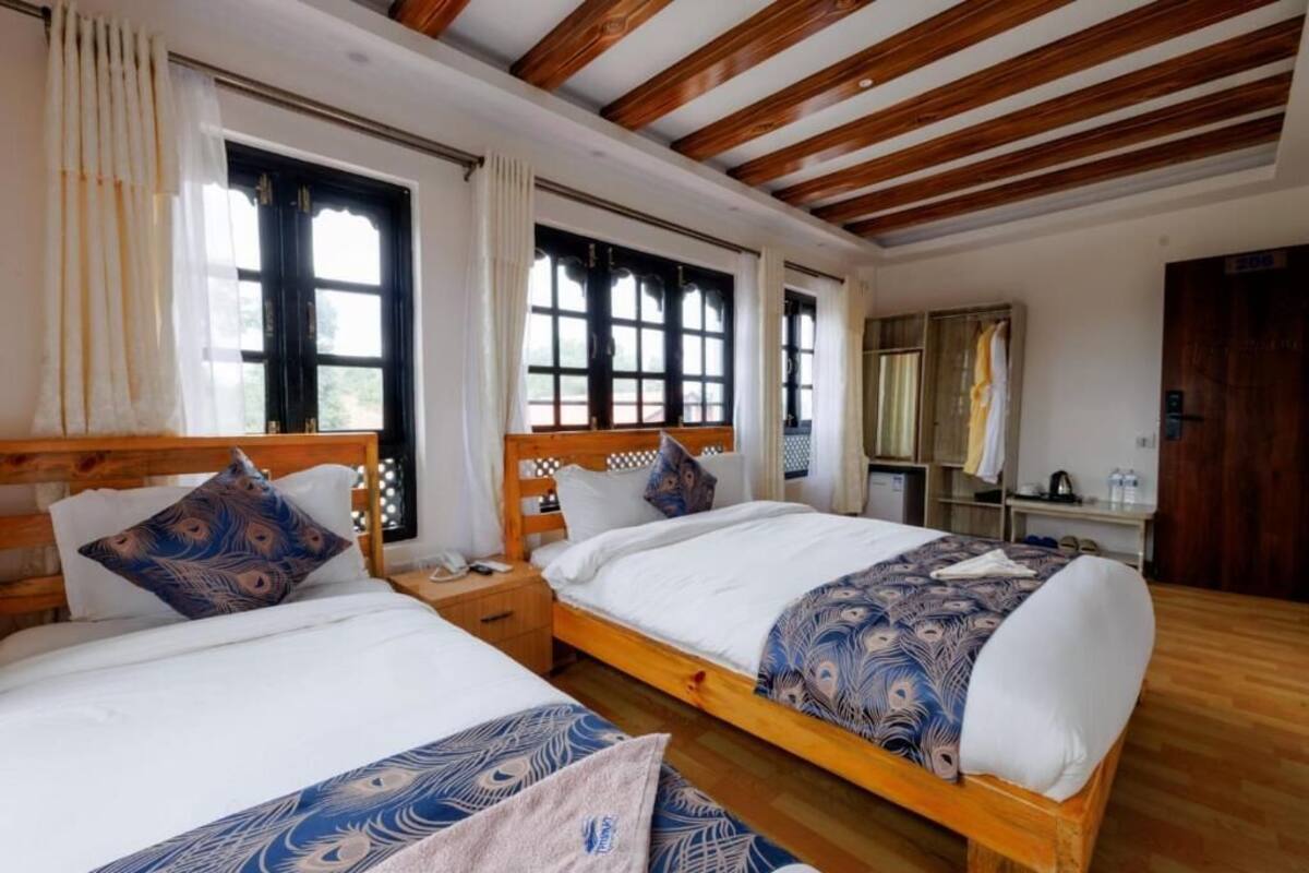 A room with two wooden beds, white bedding, and a wooden ceiling.