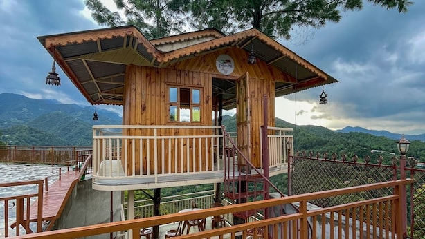 Una cabaña de madera con balcón, una escalera y vistas a las montañas.