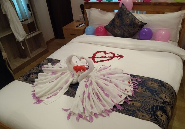 Ein ordentlich bezogenes Bett mit einer Handtuchschwan-Dekoration, einem Herzdesign und Ballons.