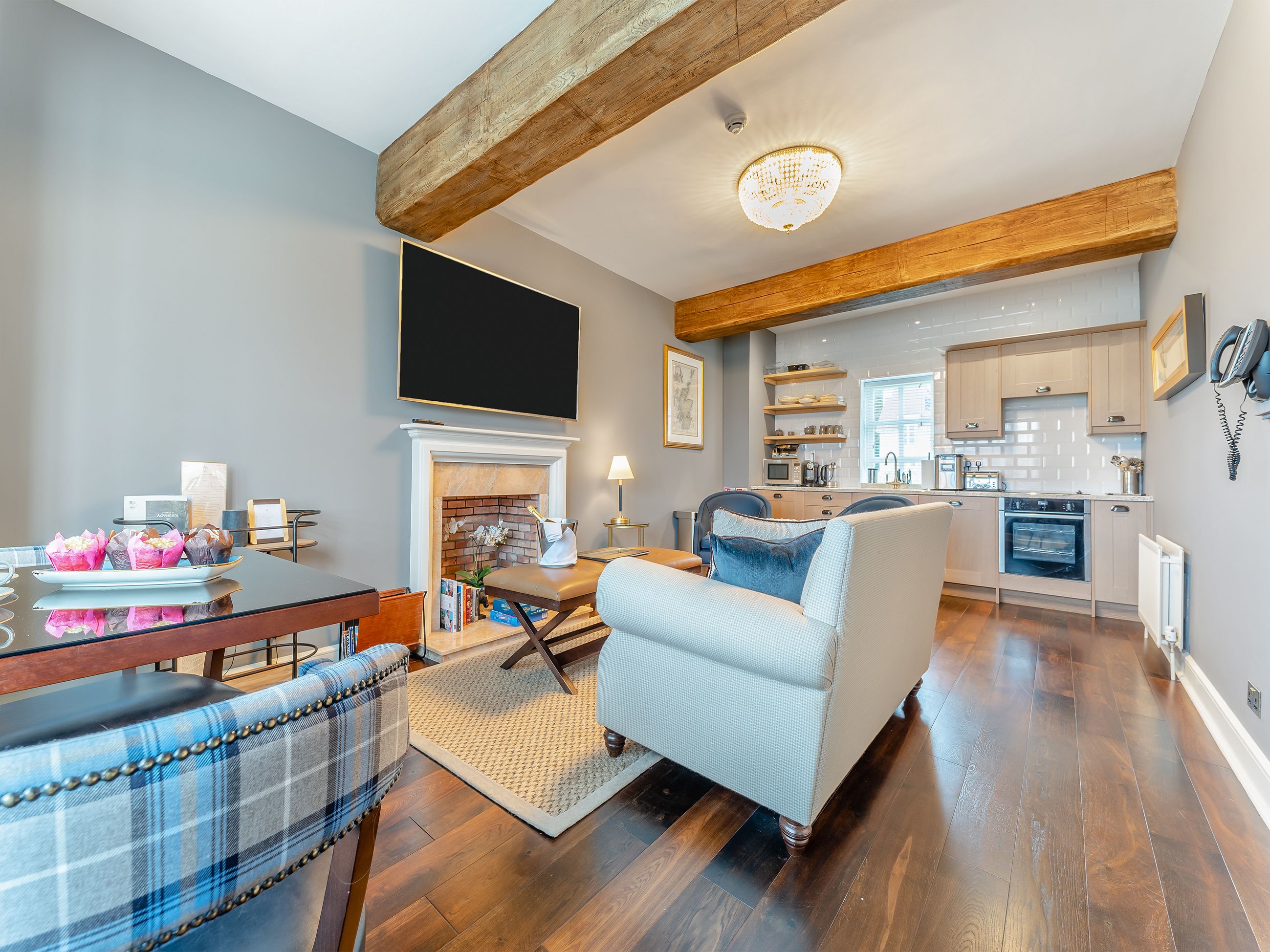 A modern living room with a fireplace, a dining area, and a kitchen in the background.