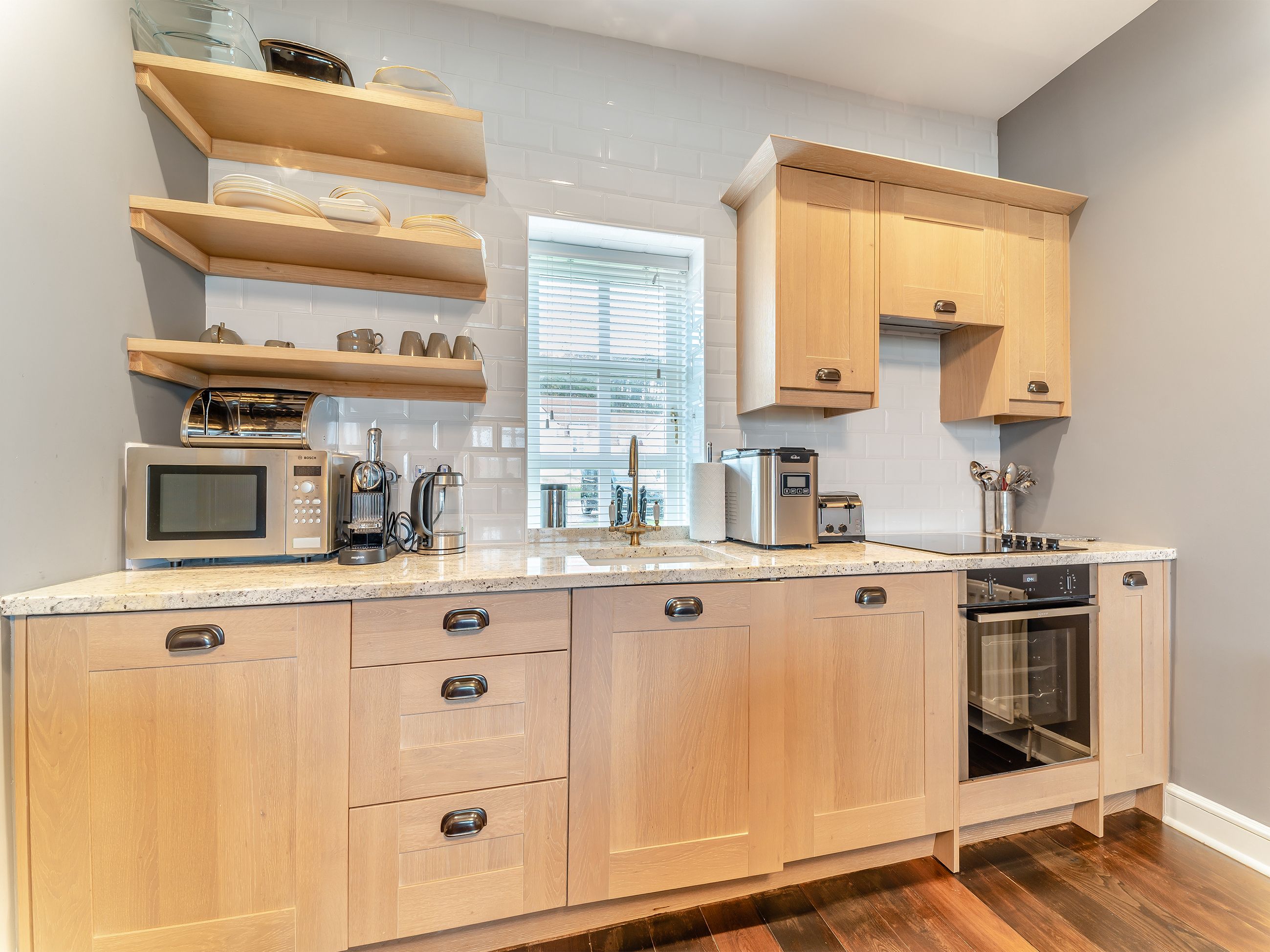 Een keuken met houten kastjes, een magnetron, een koffiezetapparaat en een broodrooster.