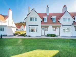 A two-story house with a red roof, white exterior, and a well-maintained lawn.