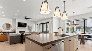 A modern kitchen with a central island, built-in appliances, and pendant lighting. - Modern Oasis at Desert Color (by Ember Stays) (St. George)