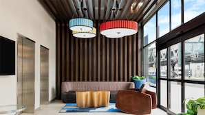 Un hall d’entrée moderne doté d’un espace salon, de grandes fenêtres et d’un plafond orné de luminaires suspendus.