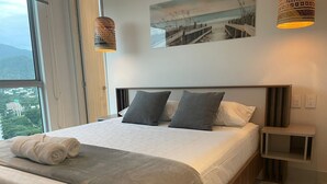 Une chambre à coucher moderne, dotée d’un grand lit, de deux lampes de chevet, d’une table de chevet et offrant une vue sur l’extérieur par une fenêtre.